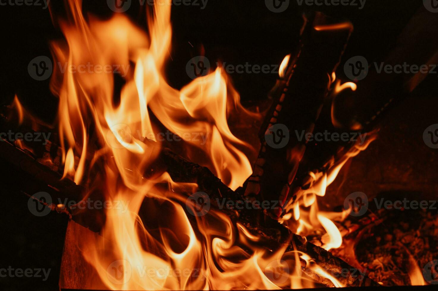 A bonfire in close-up, flames, charred pieces of logs and ashes in the open air. Camping. photo