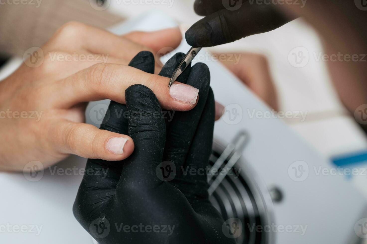 A manicure master gives a manicure to a girl in the salon. Close-up. The manicure master cuts the cuticle and burrs with manicure scissors. photo