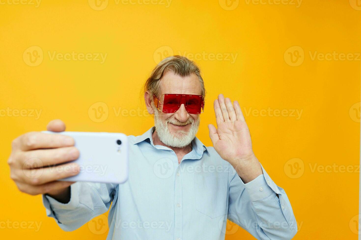 Photo of retired old man blue shirts with glasses takes a selfie isolated background