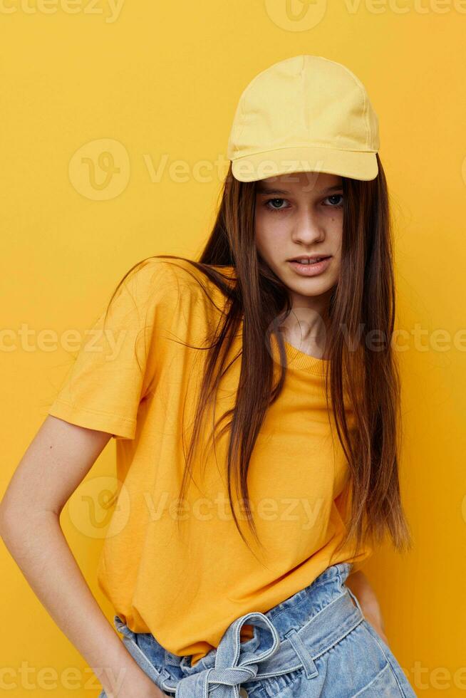 photo pretty woman posing in a yellow T-shirt and cap isolated background