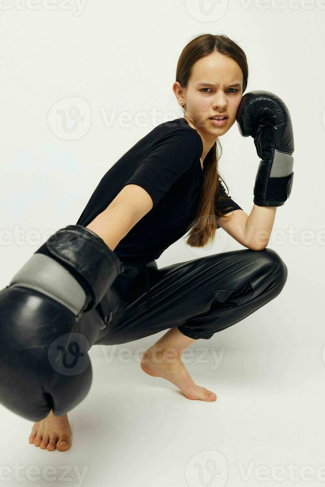 hermosa niña en boxeo guantes en el piso en negro camiseta ligero antecedentes foto