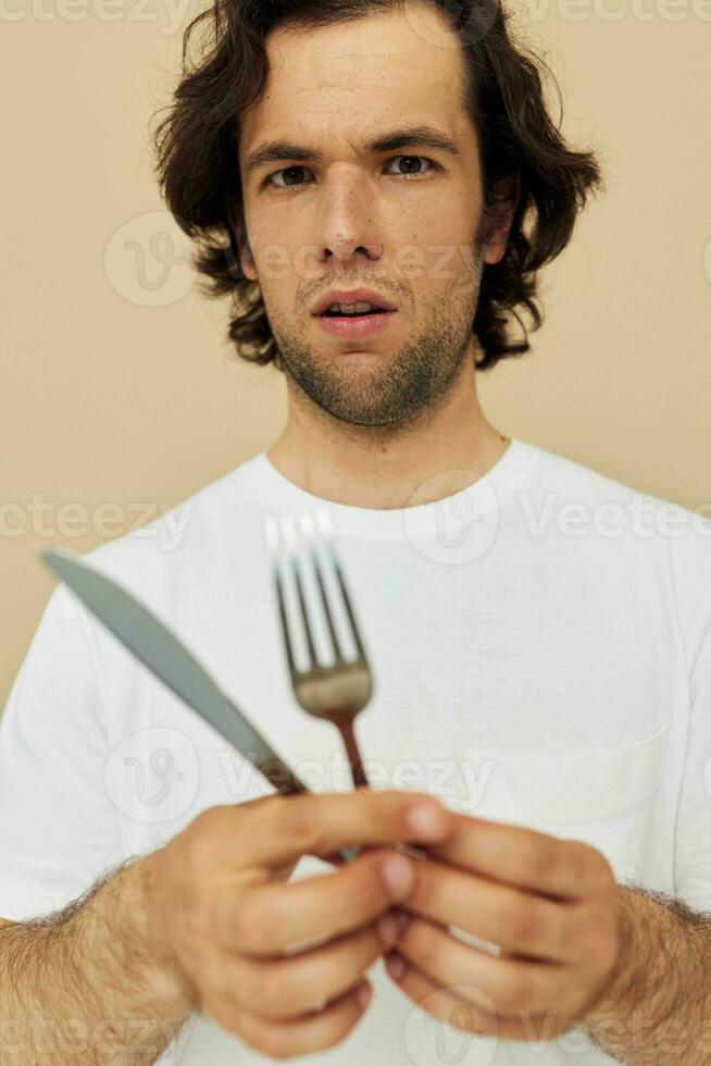 Attractive man in a white T-shirt with knife with fork isolated background photo