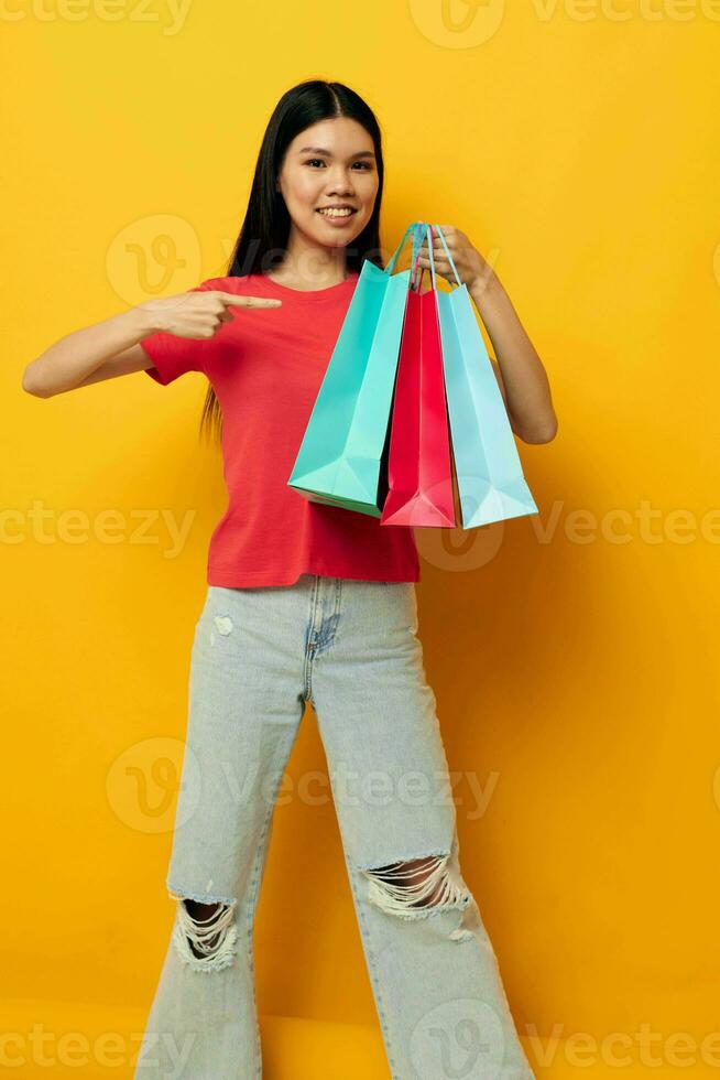 Portrait Asian beautiful young woman shopping bags in red t-shirt isolated background unaltered photo