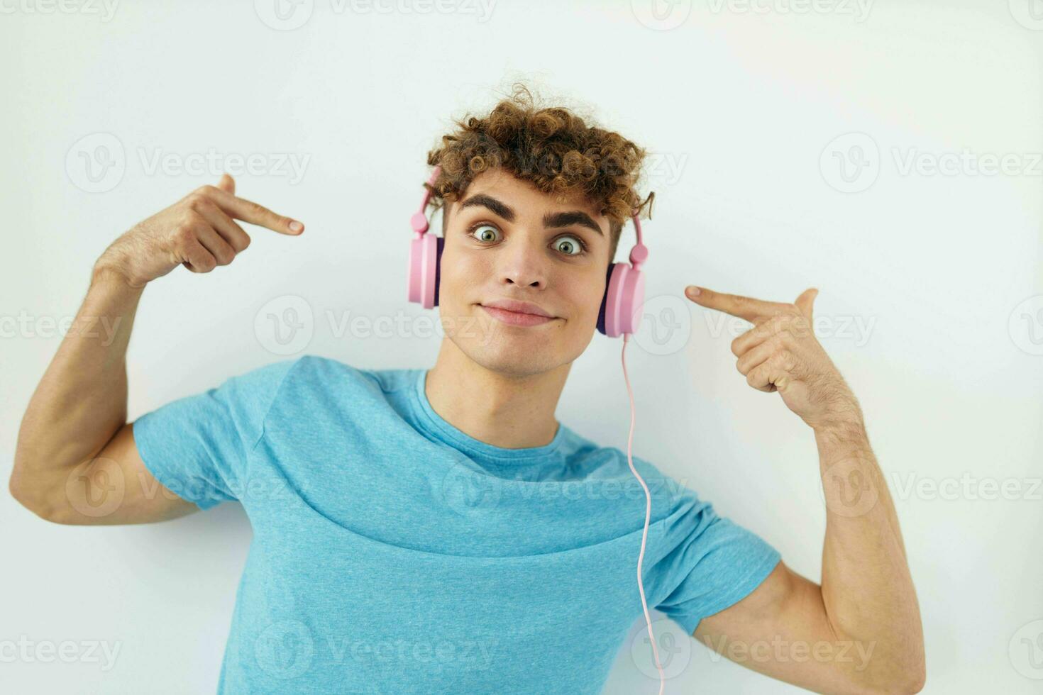 kinky guy in blue t-shirts pink headphones fashion light background photo