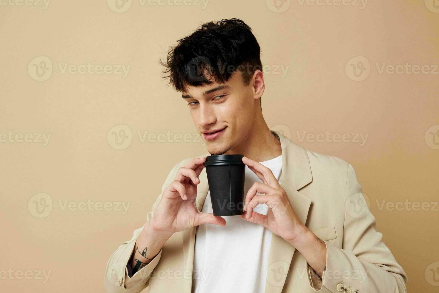 portrait of a young man a man in a light jacket a glass with a drink light background unaltered photo