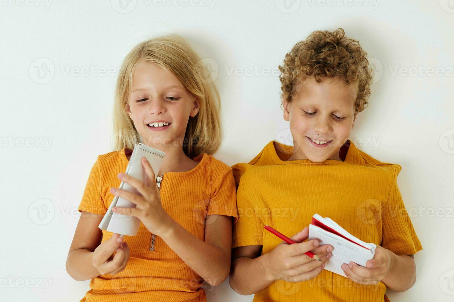 Small children lie on the floor with notepads and pencils isolated background unaltered photo