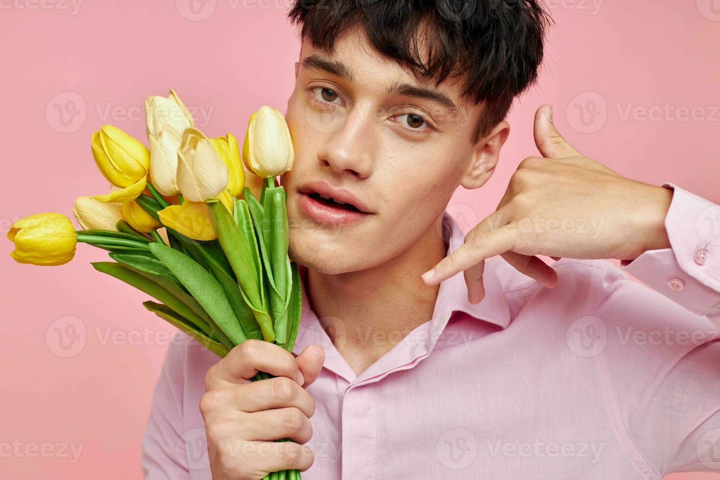 handsome guy in a pink shirt with a bouquet of flowers gesturing with his hands isolated background unaltered photo