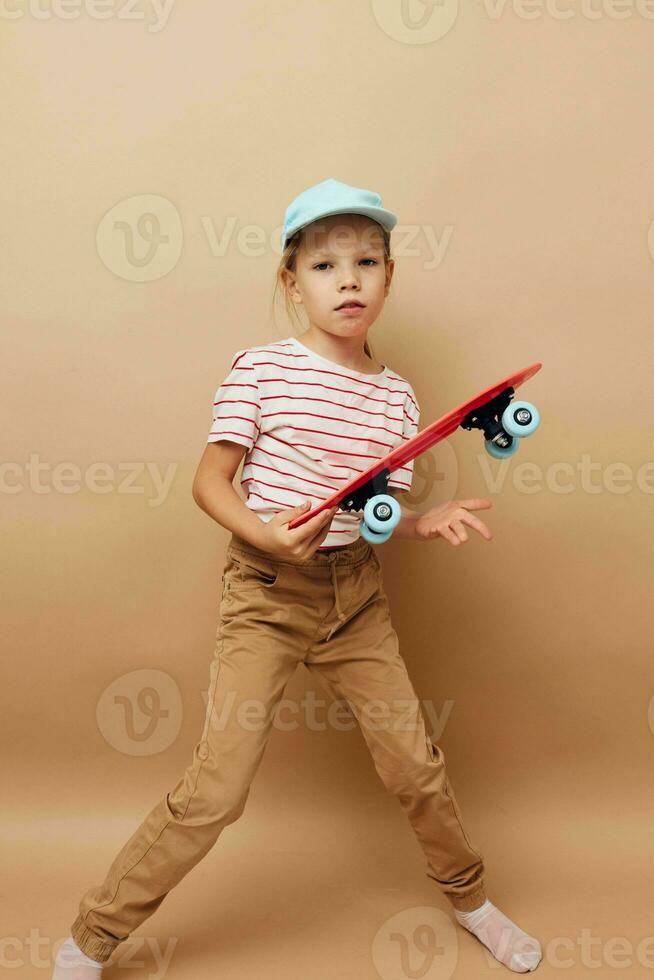 linda niña patineta en mano posando bebé ropa divertido aislado antecedentes foto