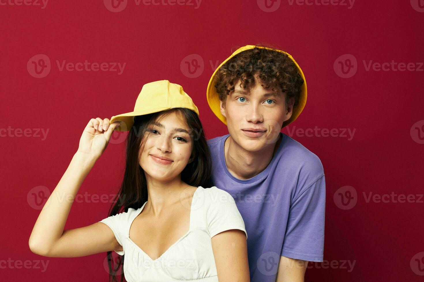 young man and girl in colorful t-shirts stylish clothes hats red background photo