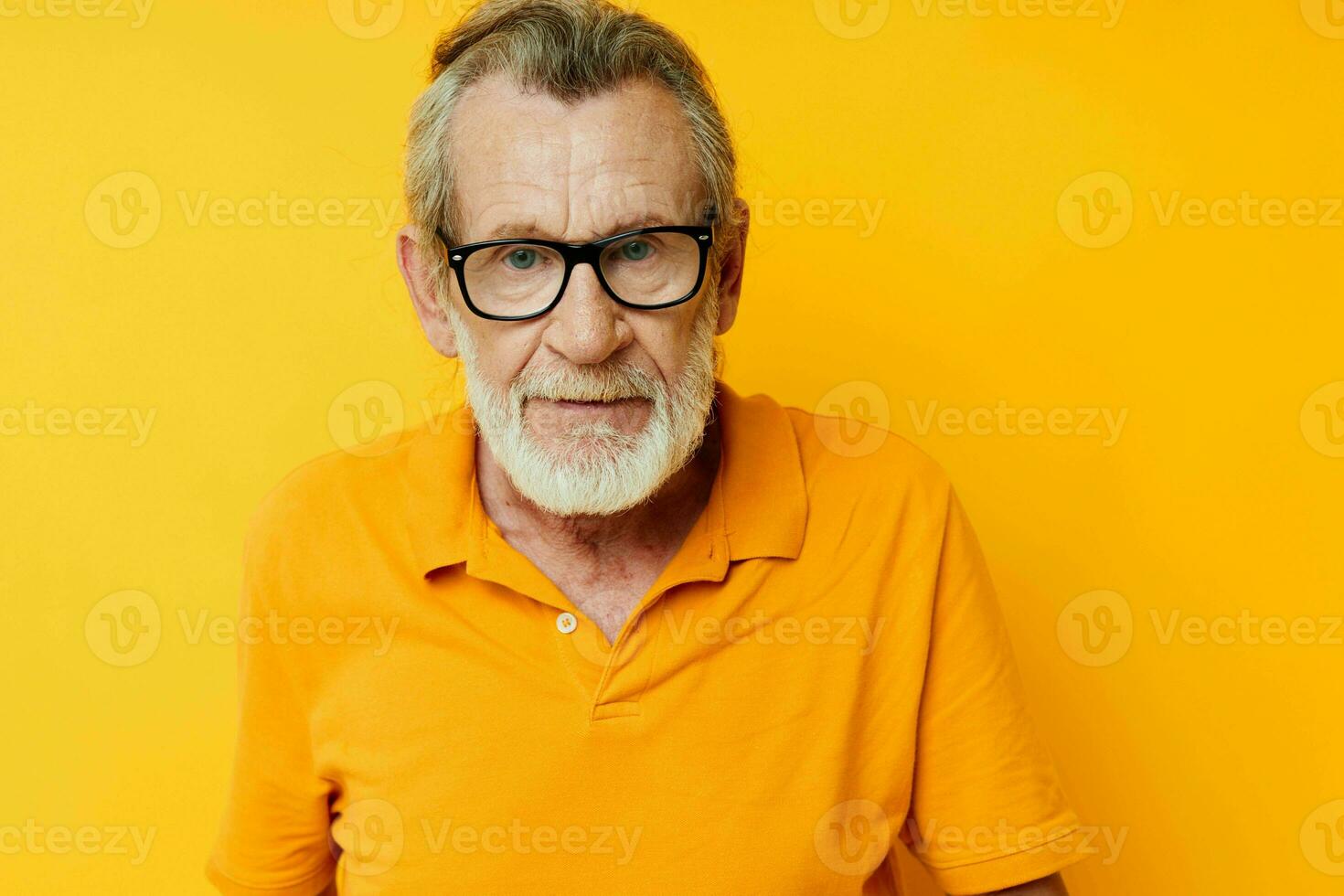 Portrait elderly man posing yellow tshirt glasses yellow background photo