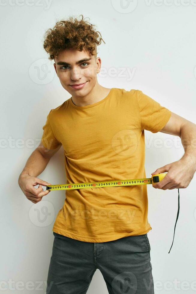 handsome guy measuring tape measure in yellow t-shirt Lifestyle unaltered photo