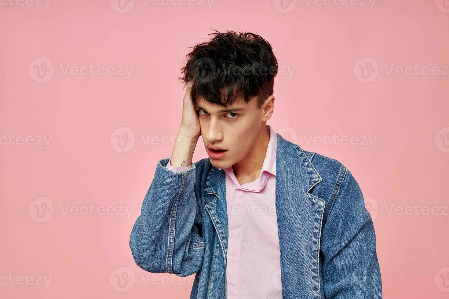 retrato de un joven hombre en juventud elegante ropa mezclilla chaqueta posando rosado antecedentes inalterado foto