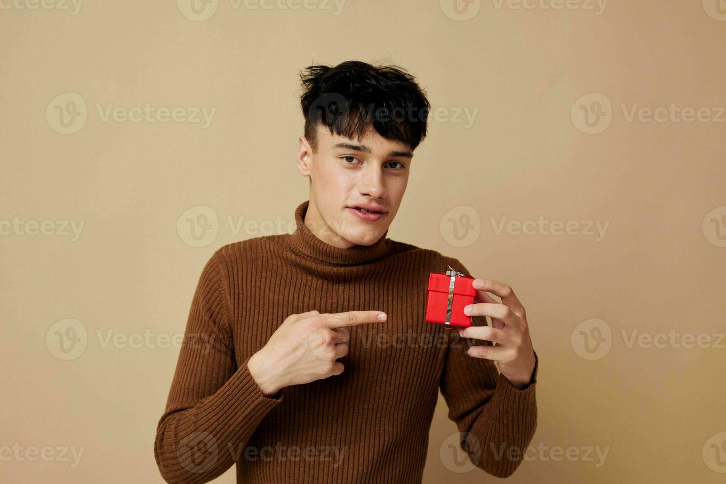 handsome guy brown turtleneck posing fashion small gift box light background unaltered photo