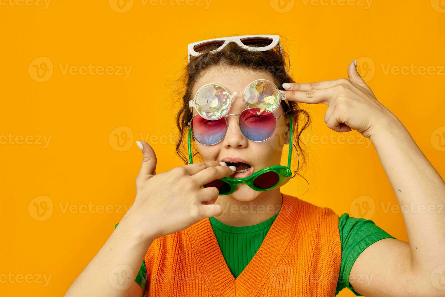 portrait of a young woman multicolored sunglasses on face posing grimace yellow background unaltered photo