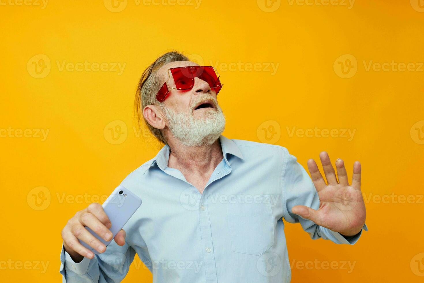 old man in fashionable red glasses with a phone yellow background photo