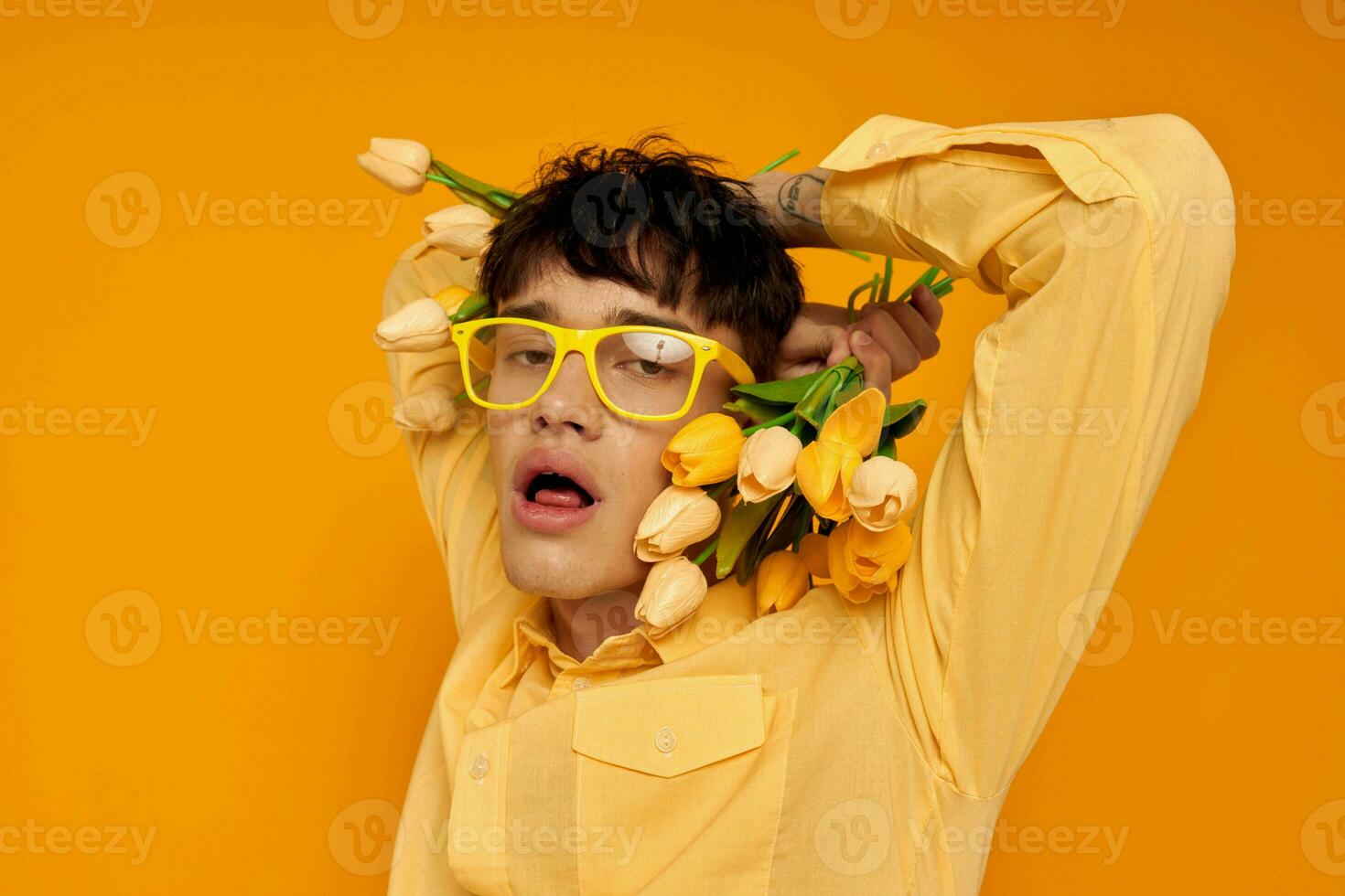Photo of romantic young boyfriend with a fashionable hairstyle in yellow shirts with flowers yellow background unaltered