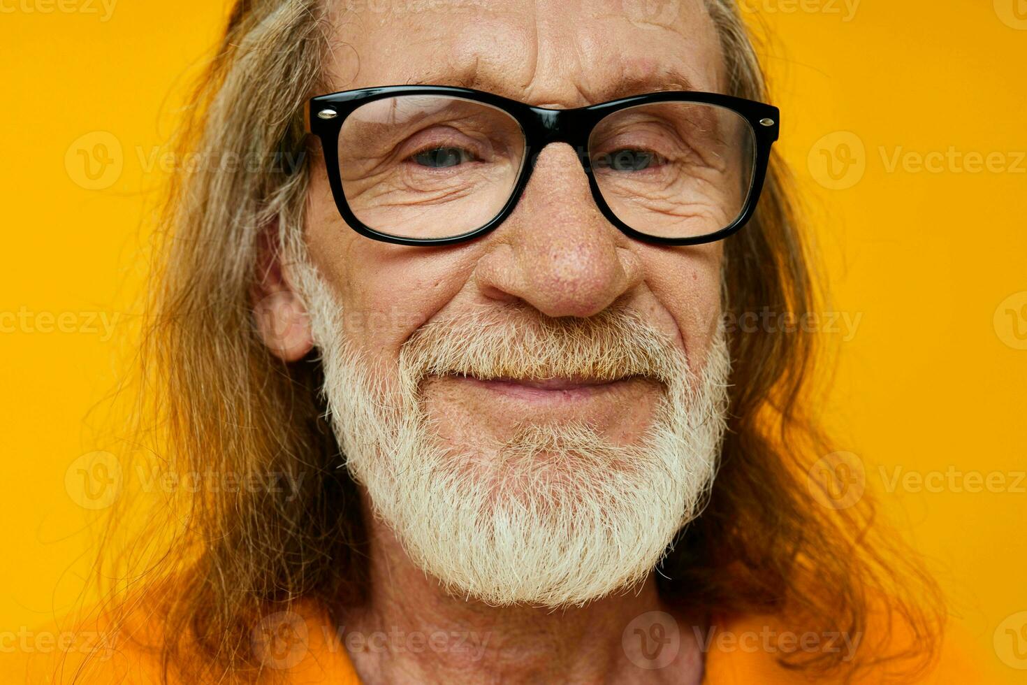 elderly gray-haired man with glasses face close-up yellow background photo