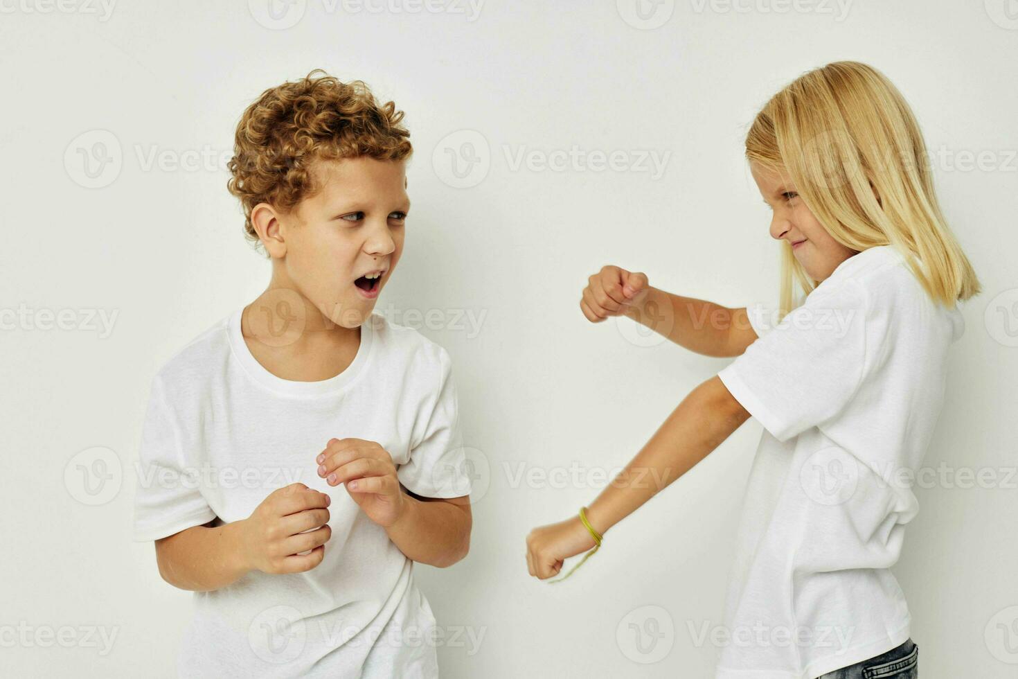 Photo of two children in white T-shirts are standing next to beige background