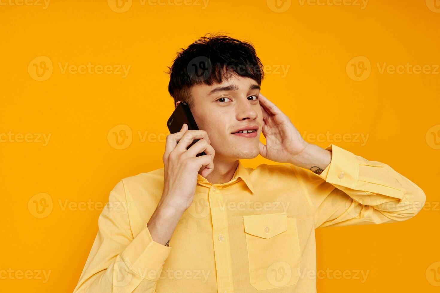 handsome man in a yellow shirt talking on the phone close-up photo