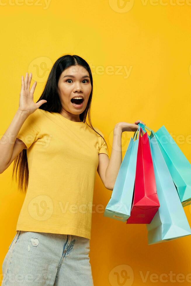 mujer en un amarillo camiseta con multicolor compras pantalones aislado antecedentes inalterado foto