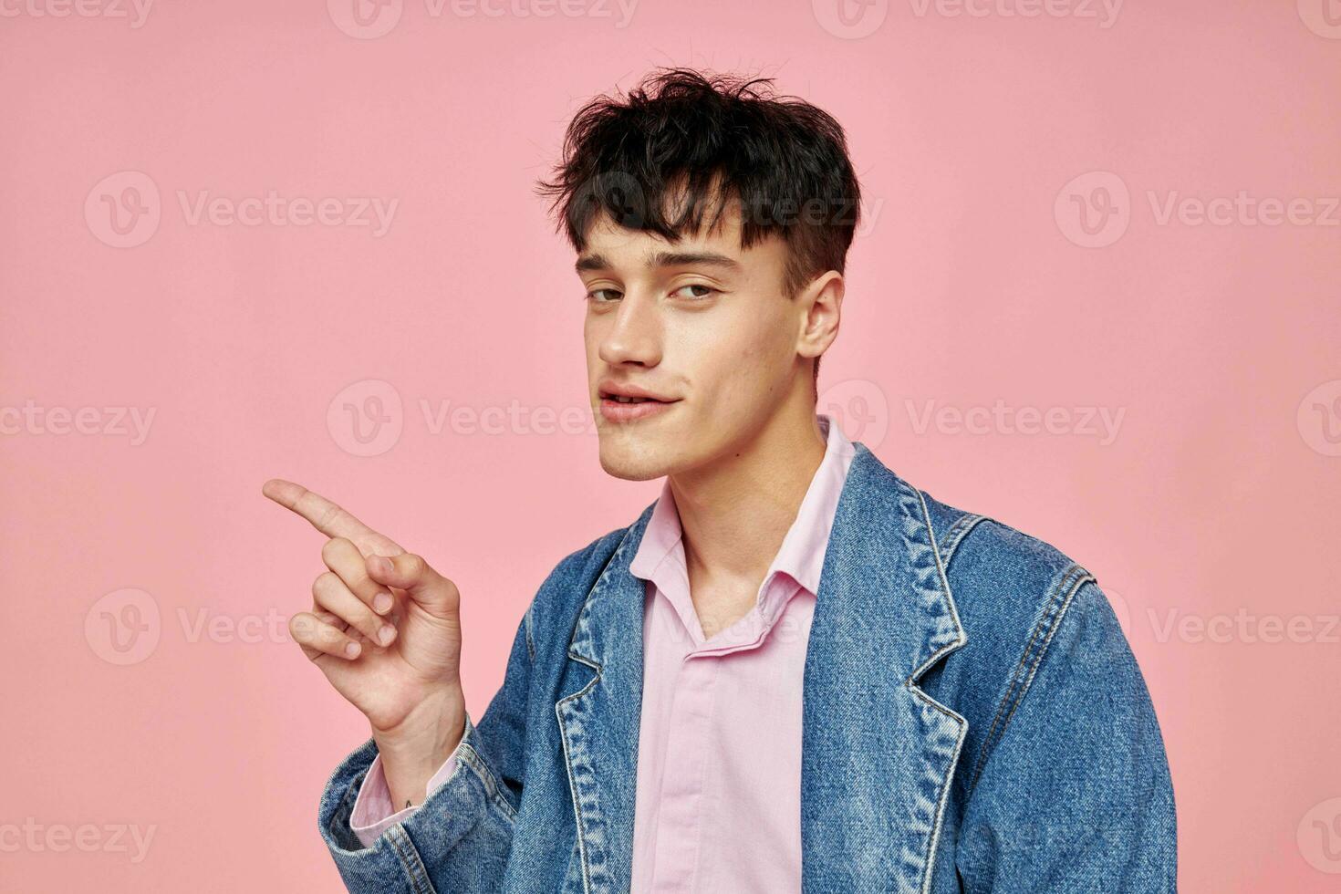 portrait of a young man in youth stylish clothes denim jacket posing pink background unaltered photo