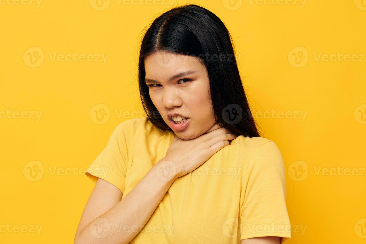 Portrait Asian beautiful young woman in a yellow t-shirt holding his head discontent studio model unaltered photo