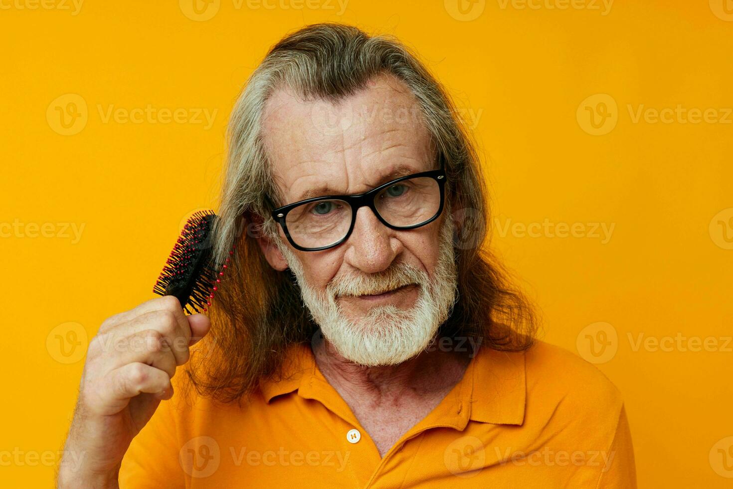 an elderly man with glasses combs his long gray hair photo