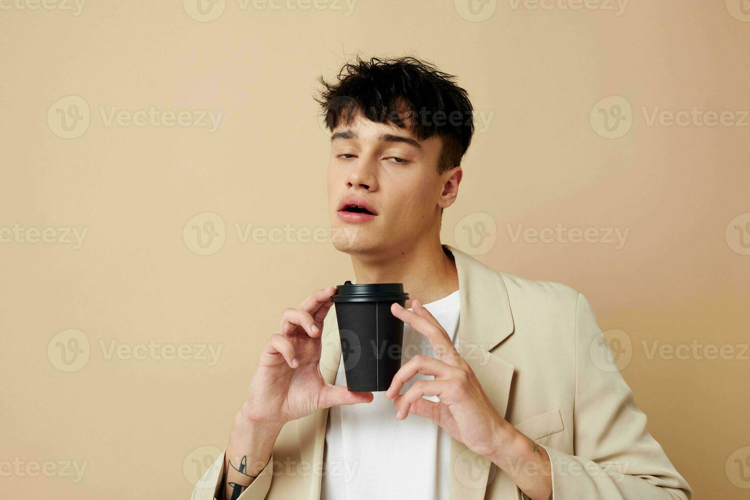 portrait of a young man a man in a light jacket a glass with a drink light background unaltered photo