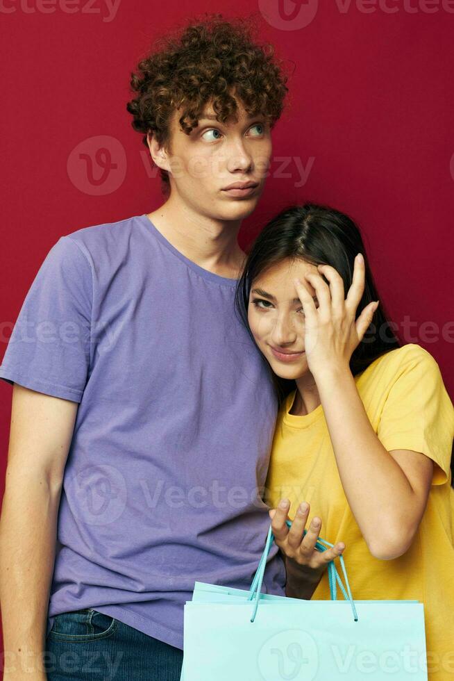 cute young couple in colorful T-shirts with bags Shopping red background unaltered photo