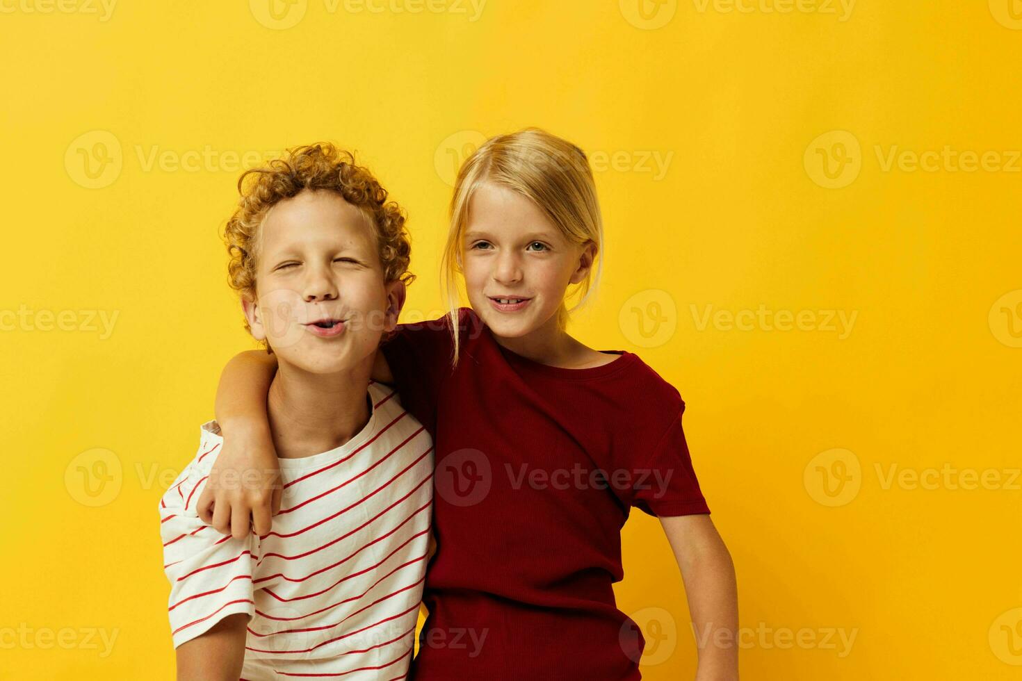 picture of positive boy and girl standing side by side posing childhood emotions yellow background photo