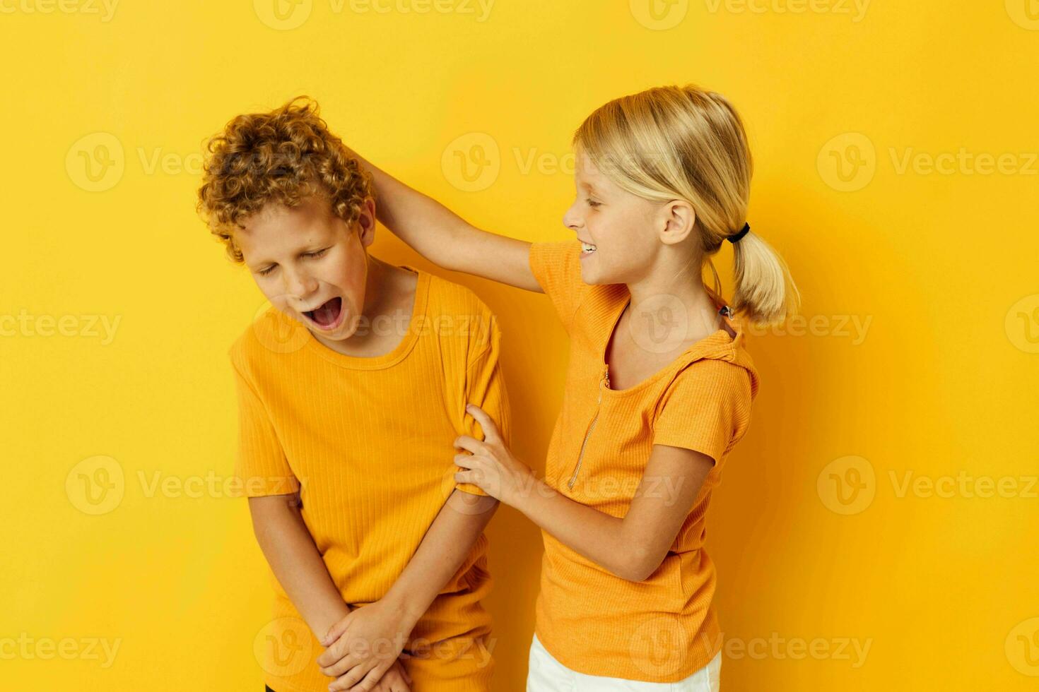 Portrait of cute children in yellow t-shirts standing side by side childhood emotions yellow background unaltered photo