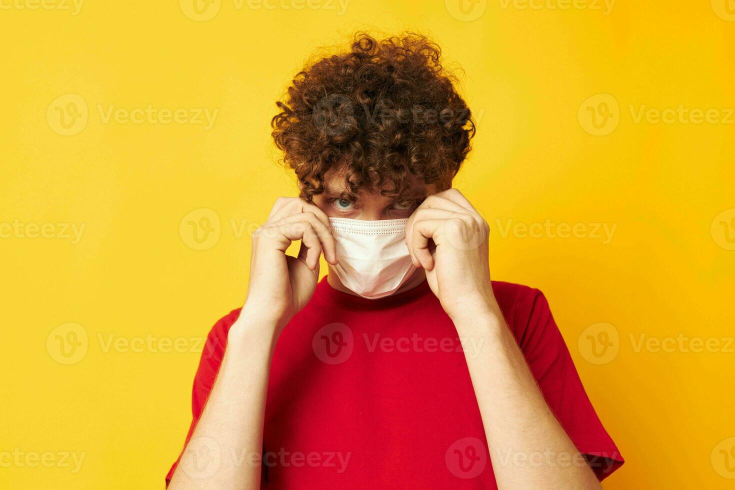 portrait of a young curly man in a red t-shirt medical mask protection monochrome shot photo