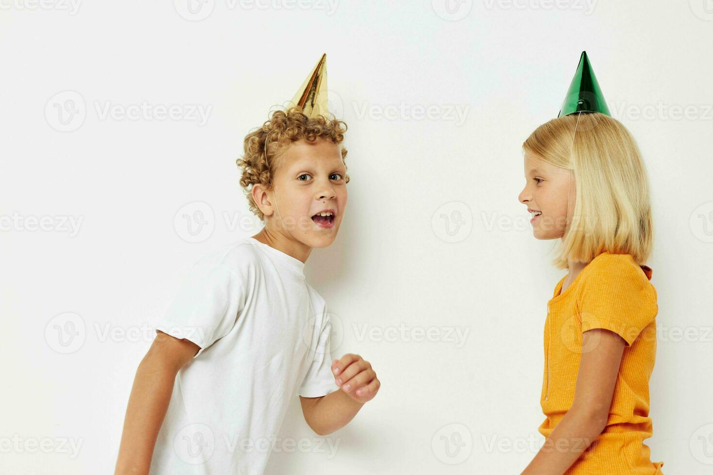 Boy and girl in multicolored caps birthday holiday emotion light background photo