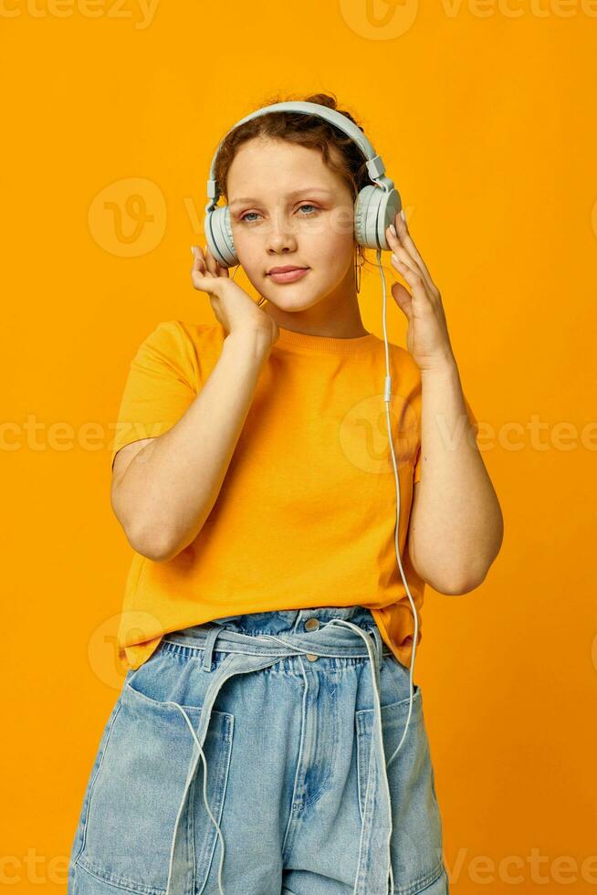 funny girl listening to music on headphones Youth style yellow background unaltered photo