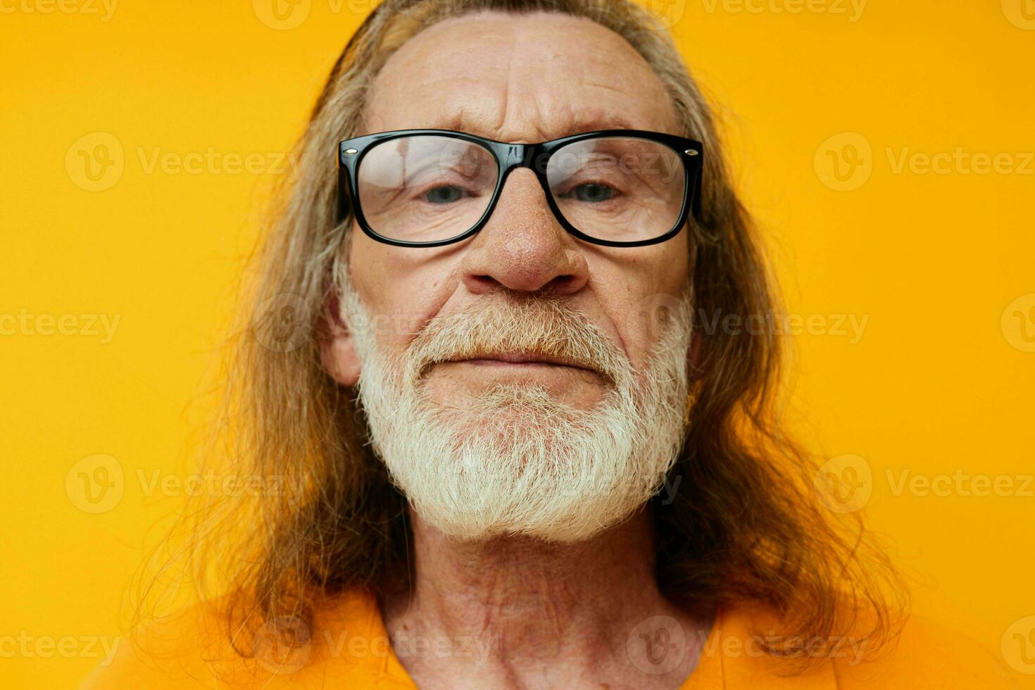 elderly gray-haired man with glasses face close-up yellow background photo