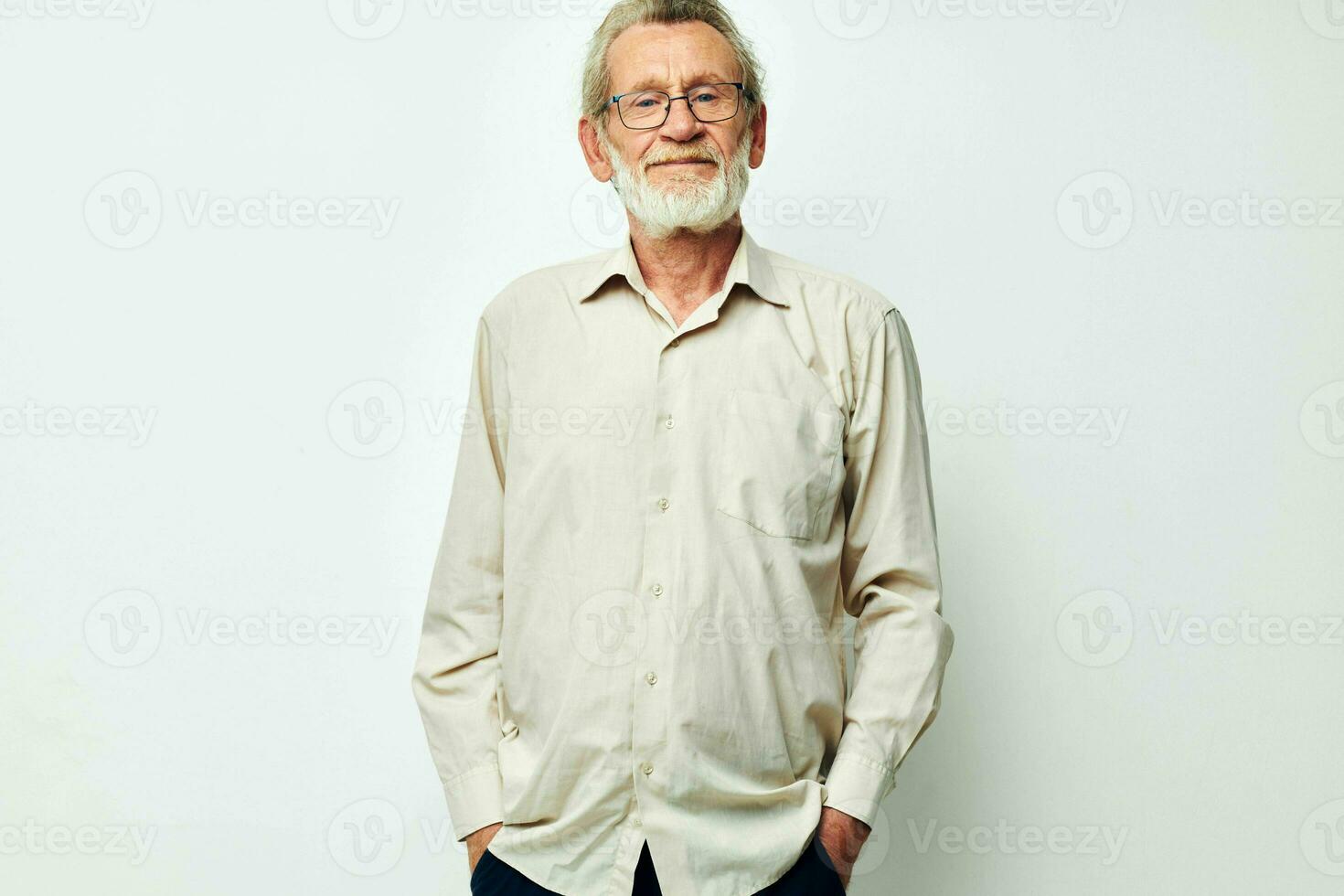 An old man stands on a gray background and looks at the camera with glasses photo