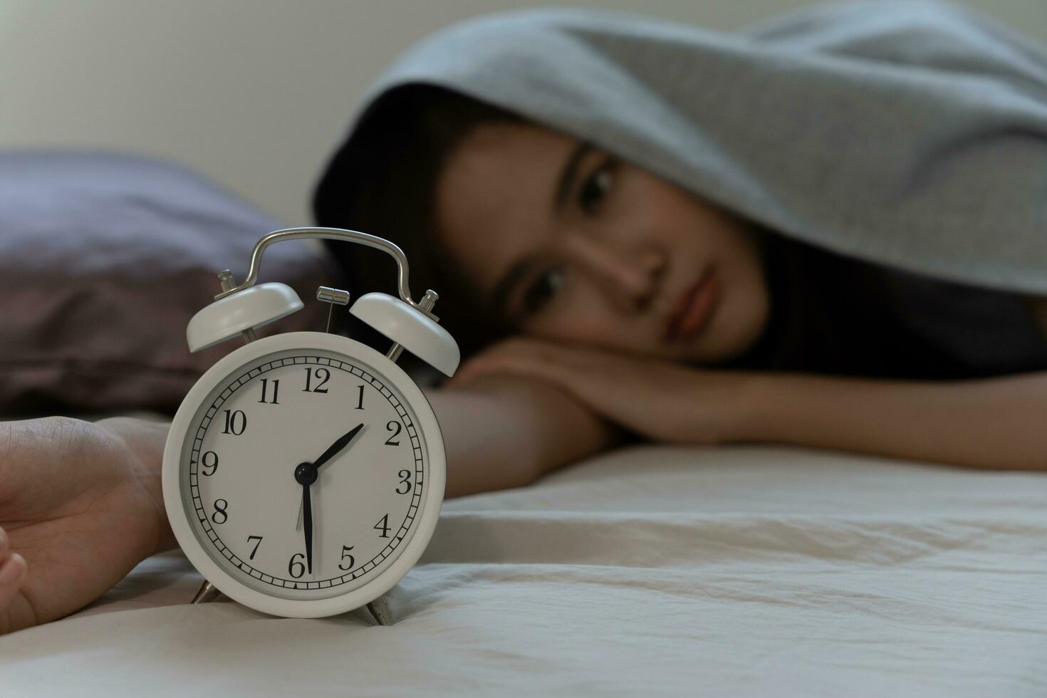 asian woman in bed late trying to sleep suffering insomnia, sleepless or scared in a nightmare, looking sad worried and stressed. Tired and headache or migraine waking up in the middle of the night. photo