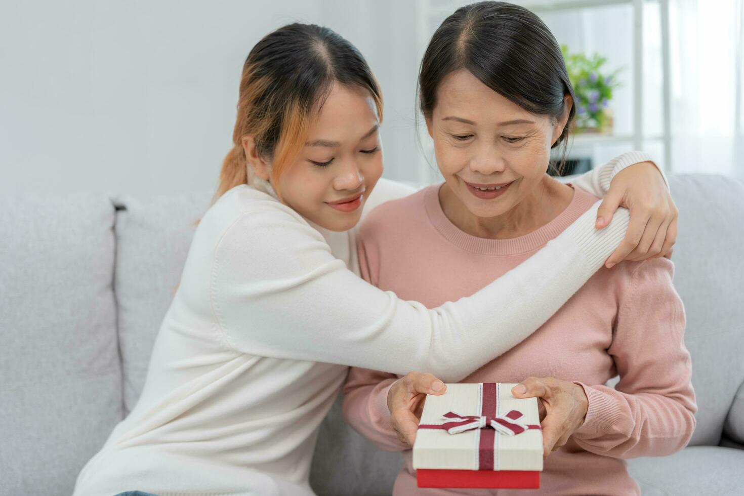 madre día, linda asiático adolescente niña dar regalo caja a maduro medio años mamá. amar, beso, cuidado, contento sonrisa disfrutar familia tiempo. celebrando especial ocasión, contento cumpleaños, contento nuevo años, alegre Navidad foto