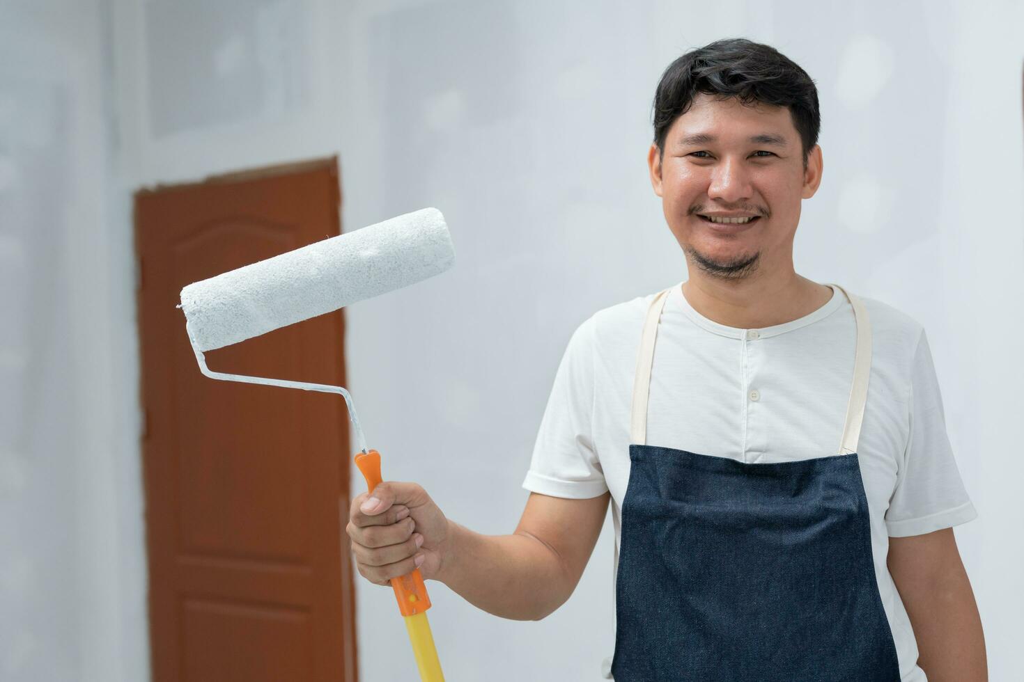 painter man, brush in hand for products to restore and paint the wall, indoor the building site of a house, wall during painting, renovation, painting, contractor, Architect, construction worker photo