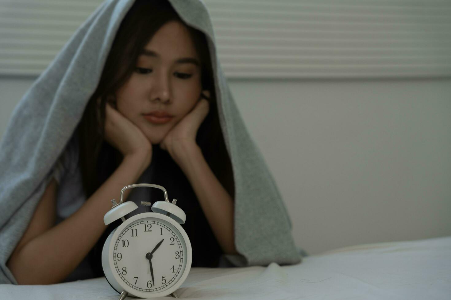 asian woman in bed late trying to sleep suffering insomnia, sleepless or scared in a nightmare, looking sad worried and stressed. Tired and headache or migraine waking up in the middle of the night. photo