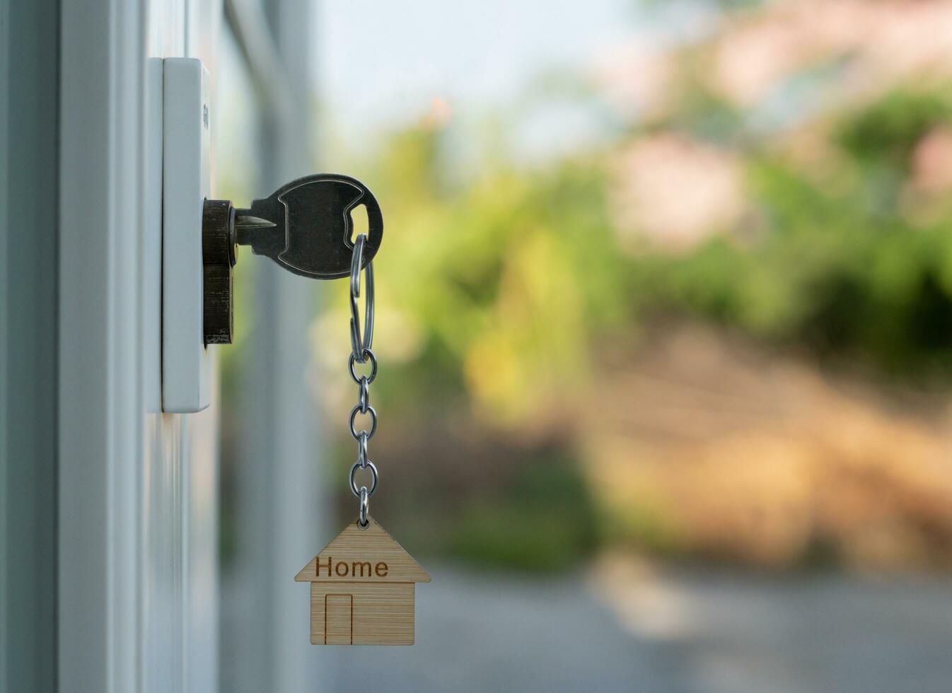 Landlord key for unlocking house is plugged into the door. Second hand house for rent and sale. keychain is blowing in the wind. mortgage for new home, buy, sell, renovate, investment, owner, estate photo