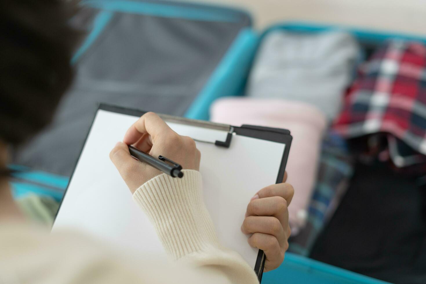 Travel bag. female are checking the detail and quantity of items used during the trip by checklist. Young women are prepare clothes and personal belongings. Pack your luggage before travel. photo