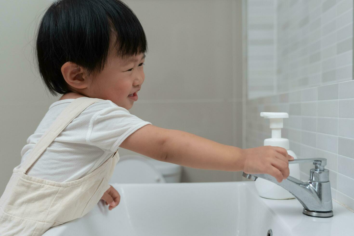 la mano del niño pequeño cerró el grifo en el fregadero en casa con mamá. la madre enseña al niño a ahorrar agua. sigue cerrando el agua para ahorrar energía mundial y proteger el medio ambiente, día mundial del agua foto