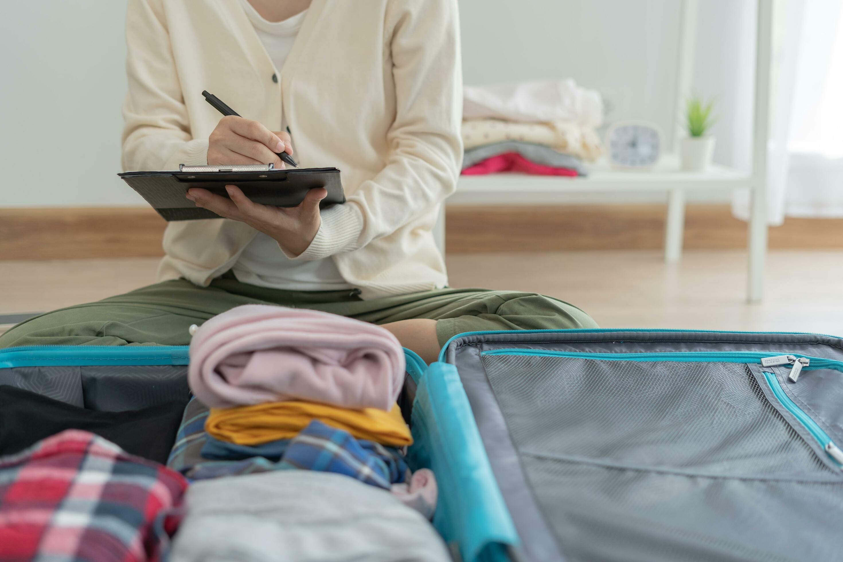 Travel bag. female are checking the detail and quantity of items used  during the trip by checklist. Young women are prepare clothes and personal  belongings. Pack your luggage before travel. 25025441 Stock