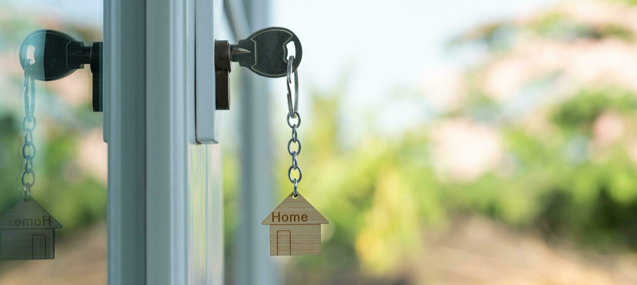 Landlord key for unlocking house is plugged into the door. Second hand house for rent and sale. keychain is blowing in the wind. mortgage for new home, buy, sell, renovate, investment, owner, estate photo