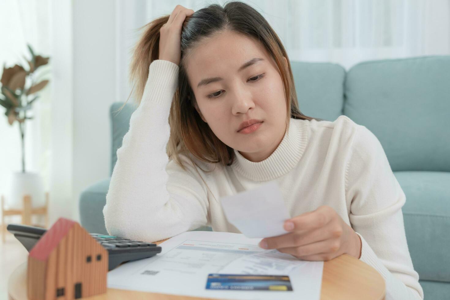 Debt house, Stressed and headache asian woman with large bills or invoices no money to pay, shortage, Financial problems, mortgage, loan, bankruptcy, bankrupt, poor, empty wallet, overdue photo
