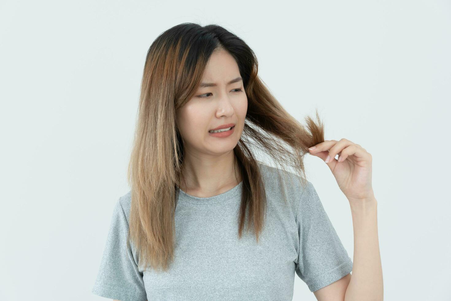 Asian woman very sad and upset looking at damaged hair, hair loss, hair thinning problem, vitamin deficiency, baldness, postpartum, biotin, zinc, menstrual or endocrine disorders, hormonal imbalance photo