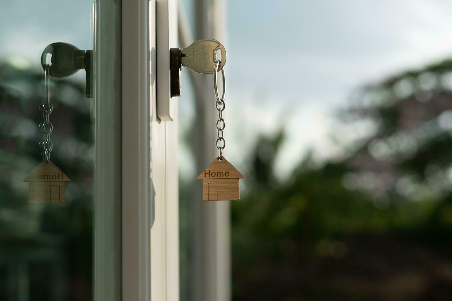 Landlord key for unlocking house is plugged into the door. Second hand house for rent and sale. keychain is blowing in the wind. mortgage for new home, buy, sell, renovate, investment, owner, estate photo