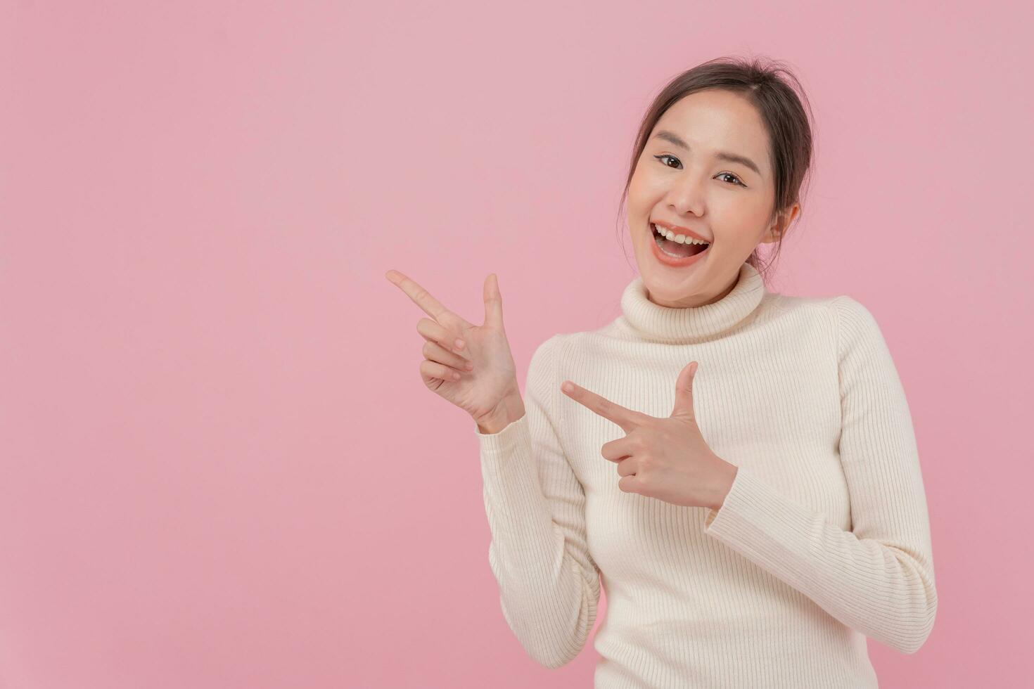 Portrait asian beautiful girl pointing blank space isolated background. Happy woman pointing on something. young female standing pointing finger sideways, billboard, introduction, advertisement, space photo