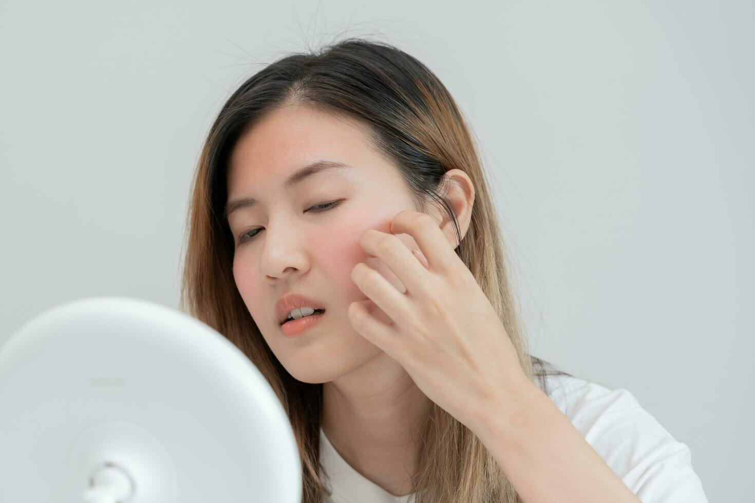 Young woman asian are worried about faces Dermatology and allergic to steroids in cosmetics. sensitive skin, red face from sunburn, acne, allergic to chemicals, rash on face. skin problems and beauty photo